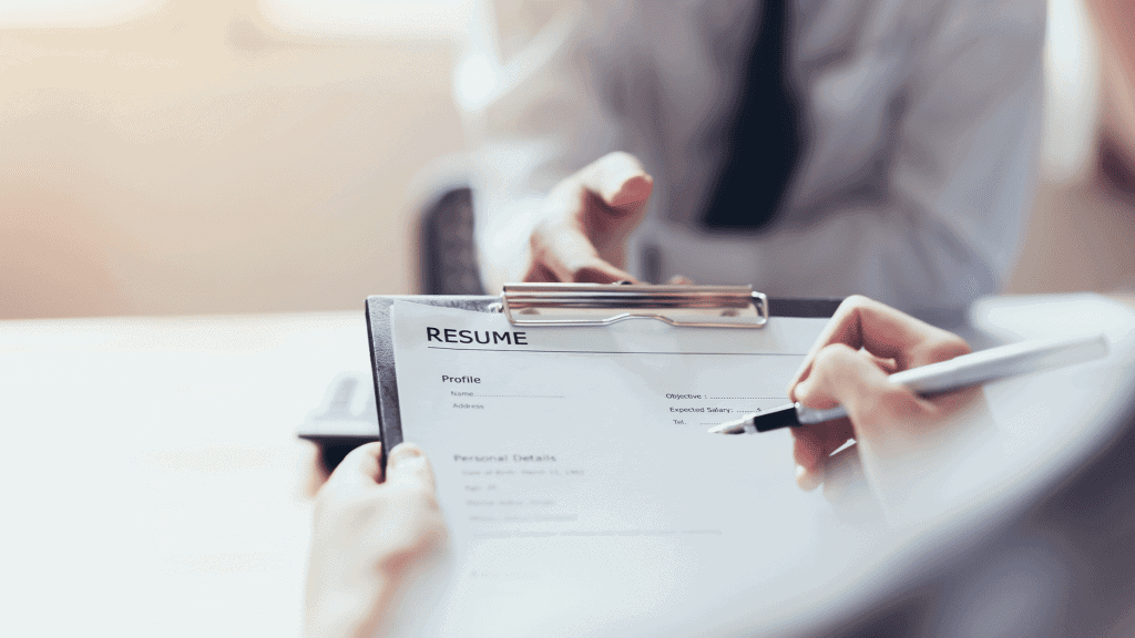 Close-up of someone writing on a printed resume with a pen