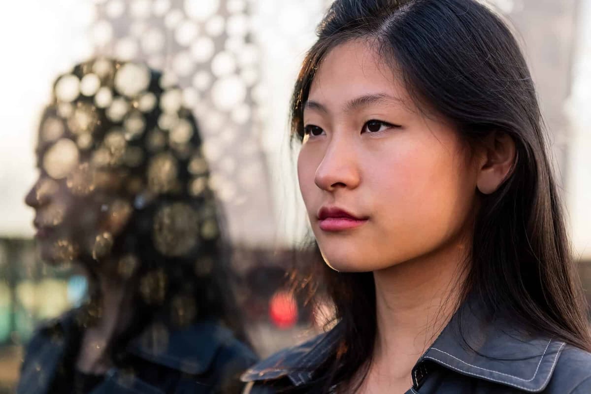 A woman looking into the distance with blurred city lights behind her