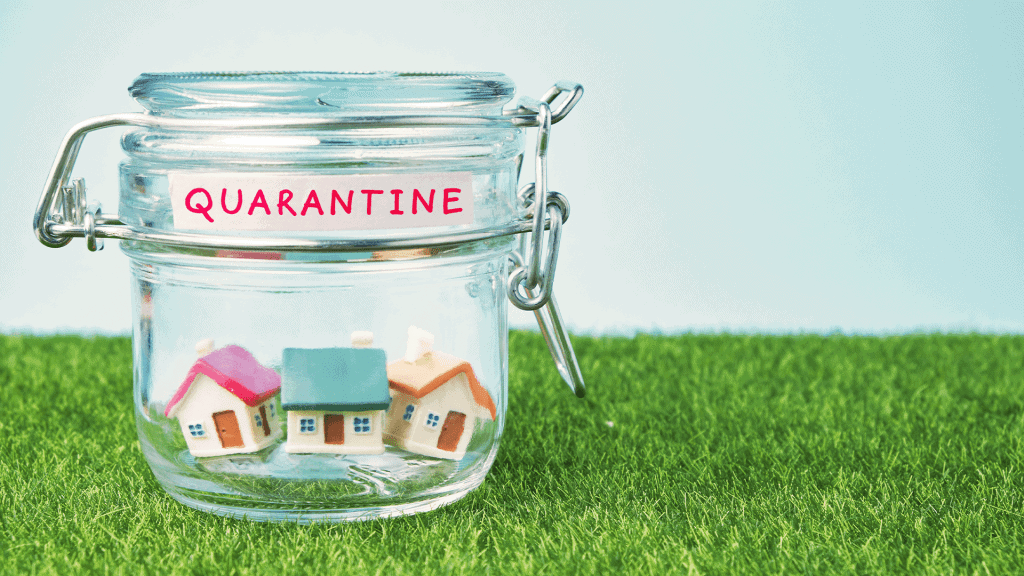 A preserving jar labelled quarantine with small model houses inside, standing on grass