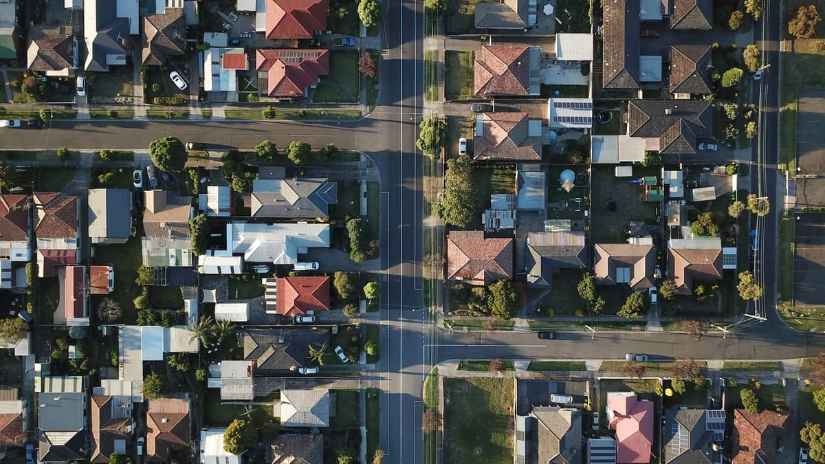 A wide, ordinary Australian suburban street under a big sky, far from the tourist waterfront.