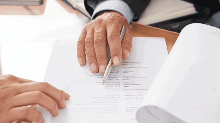 Two people at a desk going over a printed document together