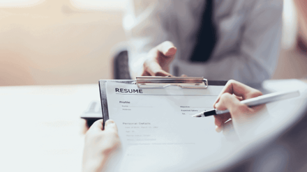 Close-up of someone writing on a printed resume with a pen