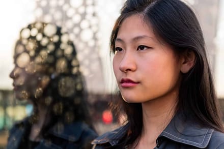 A woman looking into the distance with blurred city lights behind her