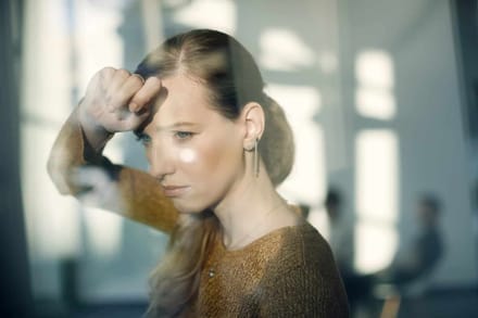 A double exposure of a woman with her hand raised to her head