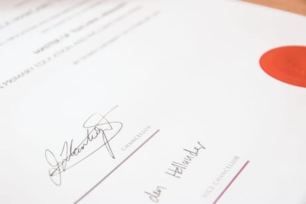 A university degree certificate with a red wax seal and chancellor signatures