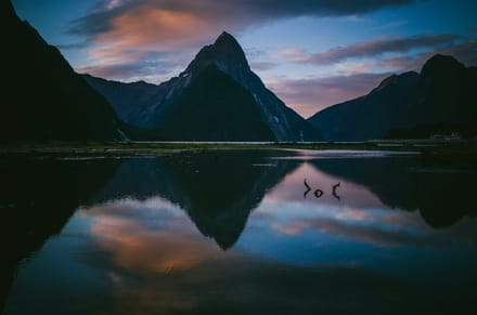 Calm New Zealand lake with mountains reflected at golden hour