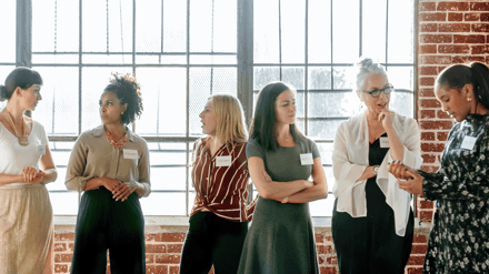 A group of women in name badges talking at a networking event