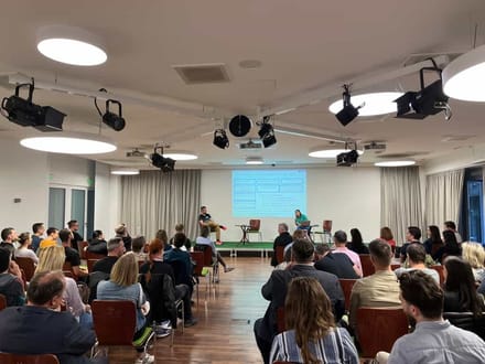 An audience seated in a lecture room facing a presentation screen