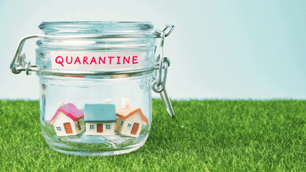 A preserving jar labelled quarantine with small model houses inside, standing on grass