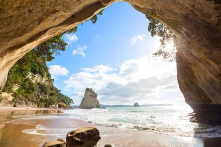 A beach framed by a rock arch on the Coromandel coast