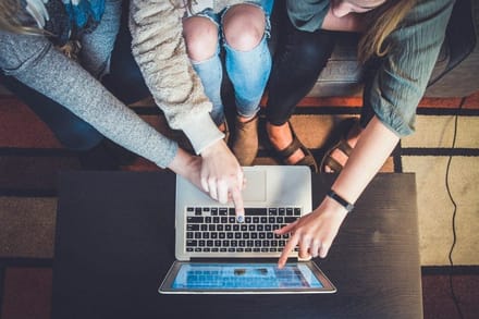 Several people gathered around a laptop, seen from above