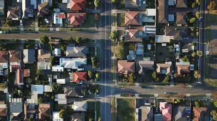 A wide, ordinary Australian suburban street under a big sky, far from the tourist waterfront.